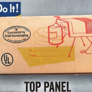 May include: A rectangular cardboard box featuring a red line drawing of a projector and a stamp that reads Guaranteed by Gvud Hussenseping. To the left, a poster displays a woman in a blue shirt and red polka dot headscarf with the text We Can Do It!