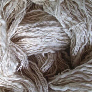 May include: A close-up of a pile of white yarn. The yarn is soft and fluffy, and it is perfect for knitting or crocheting.