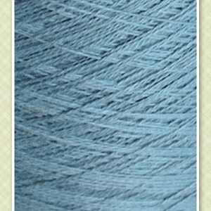 May include: Close-up of a light blue yarn skein with the word "REEF" printed on the label.
