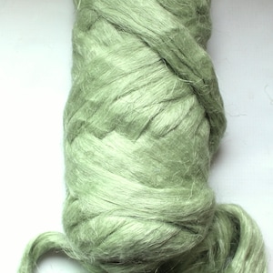 May include: A close-up of a bundle of light green fiber, likely for textile crafts. The fibers are loosely spun and have a soft, slightly shiny appearance. The bundle is tightly wound at the top and looser at the bottom.
