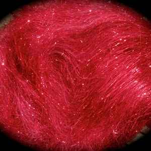 May include: A close-up of a bundle of red sparkly craft fiber. The fiber is very fine and has a slight sheen.