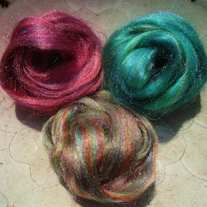 May include: Three balls of iridescent fiber, one red, one teal, and one with rainbow stripes.