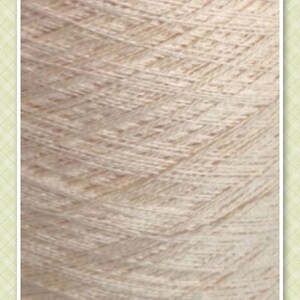 May include: Close-up of a skein of yarn in a light beige color, labeled "VANILLA". The yarn has a textured, slightly bumpy surface.