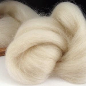 May include: A close-up of a large amount of white wool roving. The wool is soft and fluffy, and it is perfect for spinning or felting.