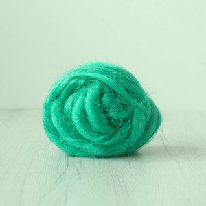 May include: A close-up of a bright teal blue ball of wool fiber. The wool is soft and fluffy, and it is perfect for crafting.