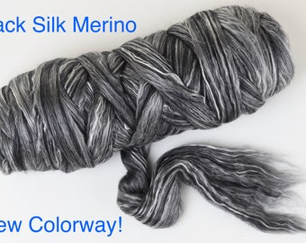 May include: A braided bundle of black, gray, and white fiber roving with a soft, textured appearance. The text "Black Silk Merino" appears at the top left and "New Colorway!" is printed at the bottom left of the image.