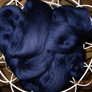 May include: A large amount of dark blue wool fiber, likely alpaca or merino, is shown in a white wire basket. The wool is soft and fluffy, and it is perfect for spinning or felting.