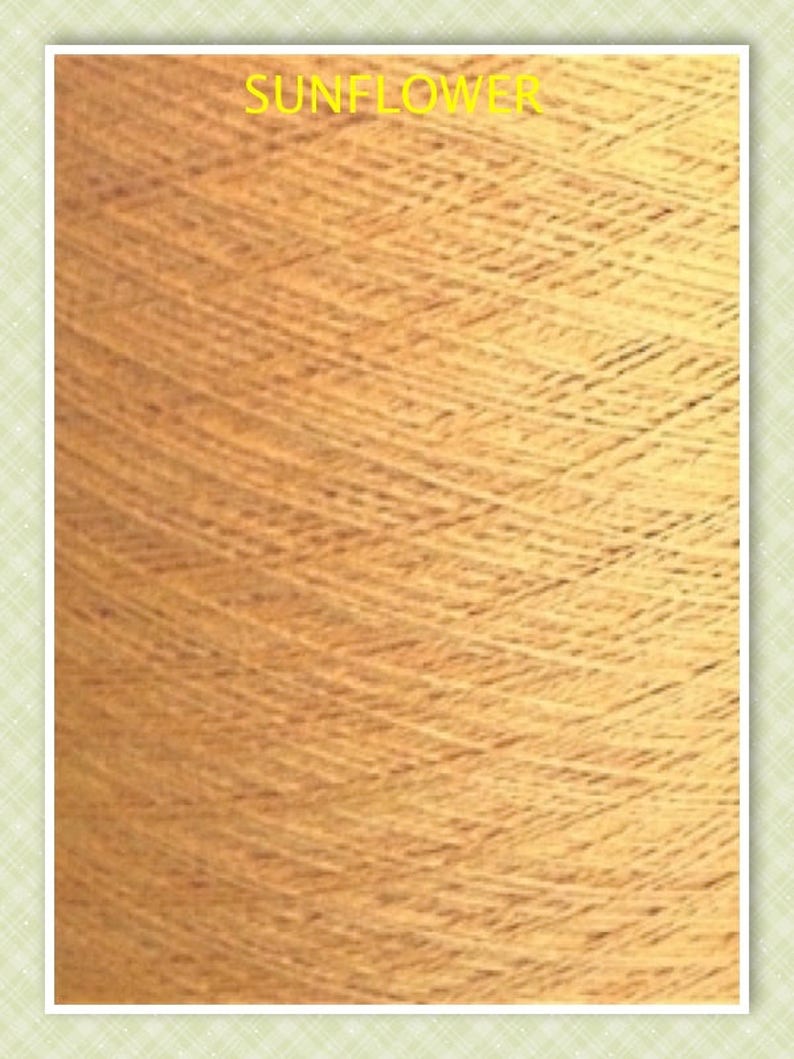 May include: A close-up of a spool of yarn in a warm, golden yellow color. The yarn is textured and has a subtle sheen. The text "SUNFLOWER" is printed on the spool.