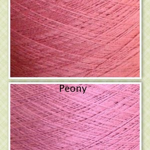 May include: Close-up of two skeins of yarn, one in a coral color and the other in a peony color. The yarn is soft and textured.