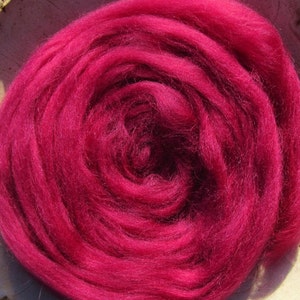 May include: A close-up of a deep pink wool roving, a type of fiber used for felting and spinning.