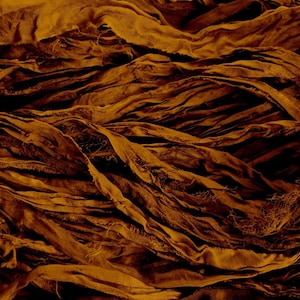 May include: A close-up of a pile of brown fabric ribbon. The ribbon is crumpled and twisted, creating a textured and abstract background.