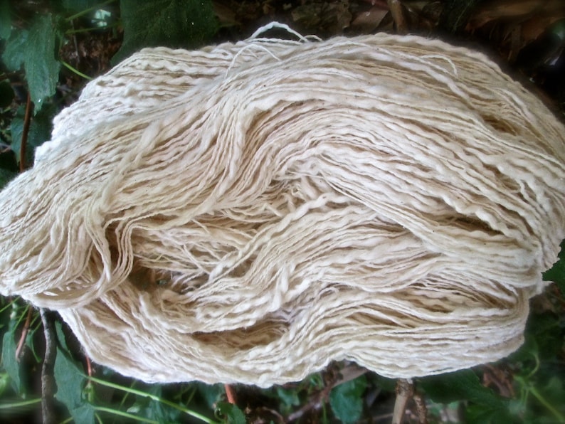 May include: A large bundle of off-white yarn, likely cotton, is piled in a loose, messy heap. The yarn is very fine and appears to be hand-spun.