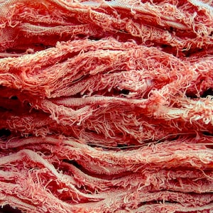 May include: Close-up of a pile of pink and white yarn, with a soft, fuzzy texture.