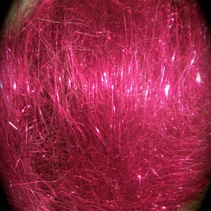 May include: A close-up of a bright pink sparkly fiber, resembling a fluffy cloud. The fibers are long and thin, creating a soft and textured appearance.