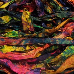 May include: A pile of colorful silk ribbon scraps in shades of yellow, orange, red, green, blue, and purple. The ribbon is tie-dyed with a variety of patterns.