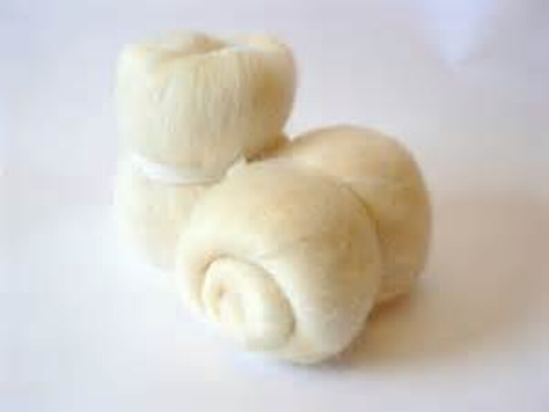 May include: A close-up of several off-white, round, and fluffy bread rolls. One stack of two rolls is tied with a white band. The rolls have a soft, textured appearance, suggesting they are freshly baked.