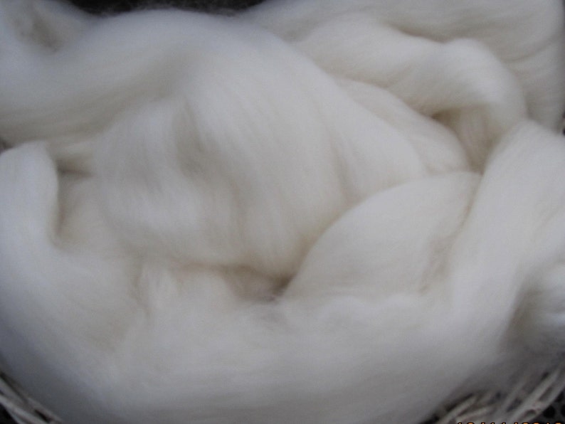 May include: A close-up of a large amount of white wool fiber. The wool is soft and fluffy, and it is perfect for spinning or felting.