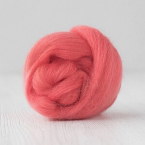 May include: A ball of coral-colored wool roving, a type of fiber used for felting and spinning.