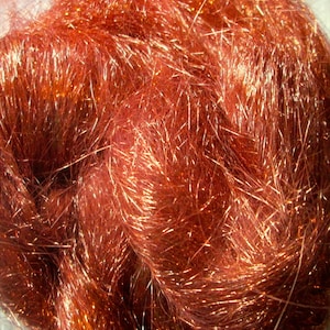 May include: A close-up of a bundle of copper-colored metallic fiber. The fibers are long and thin, and they have a shiny, iridescent finish.