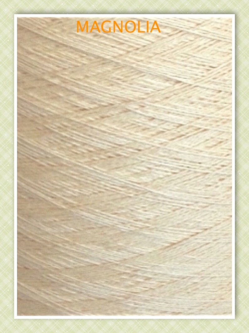 May include: Close-up of a skein of cream-colored yarn. The yarn is made of natural fibers and has a soft, textured appearance. The yarn is labeled "MAGNOLIA".