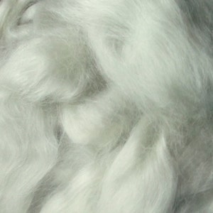 May include: A close-up of a pile of soft, white, and light green mohair yarn.