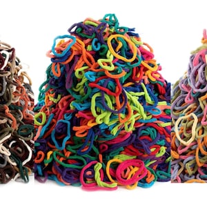 May include: Three large piles of elastic hair ties. The first pile features neutral tones like brown, black, and tan. The second pile contains vibrant, saturated colors including red, blue, green, and yellow. The third pile consists of pastel shades like pink, light blue, and lavender.