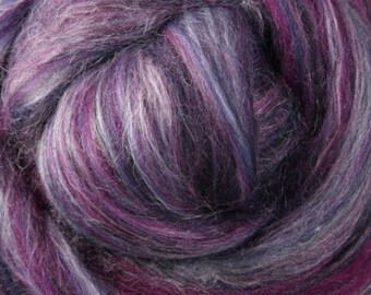May include: A close-up of a bundle of purple, blue, and white wool roving. The roving is soft and fluffy, and the colors are blended together in a beautiful way.