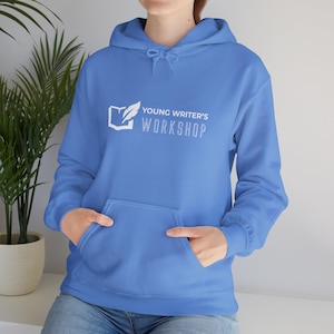 Op de afbeelding: Een lichtblauwe hoodie met een witte afbeelding van een boek met een veer en de tekst "Young Writer's Workshop".