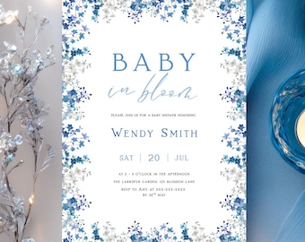 Peut inclure: Une invitation à une baby shower avec une bordure florale et le texte "Baby in Bloom". L'invitation est entourée de bougies bleues dans des bougeoirs en verre et d'une branche décorative argentée. L'invitation comprend le nom Wendy Smith et les détails de l'événement.