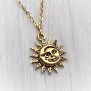 May include: Gold necklace with a sun and moon pendant. The sun has a face and the moon has a crescent shape.