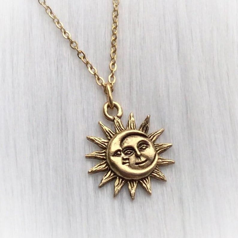 May include: Gold necklace with a sun and moon pendant. The sun has a face and the moon has a crescent shape.