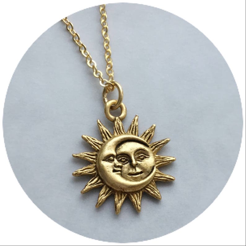 May include: Gold necklace with a sun and moon pendant. The pendant features a detailed design of a sun with a crescent moon face.