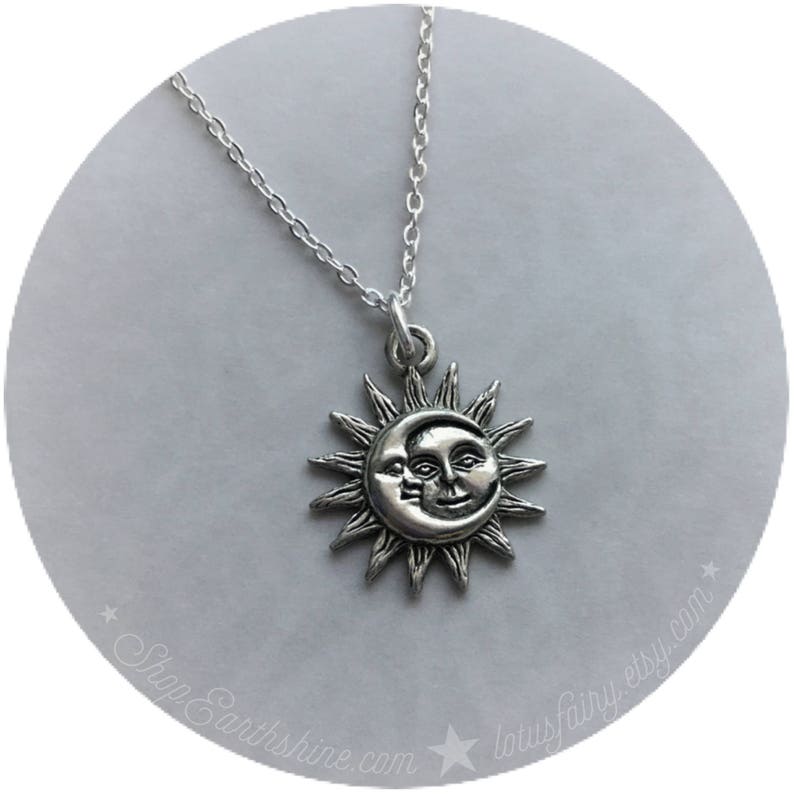 May include: Silver necklace with a sun and moon pendant. The sun has a face and the moon is a crescent shape.