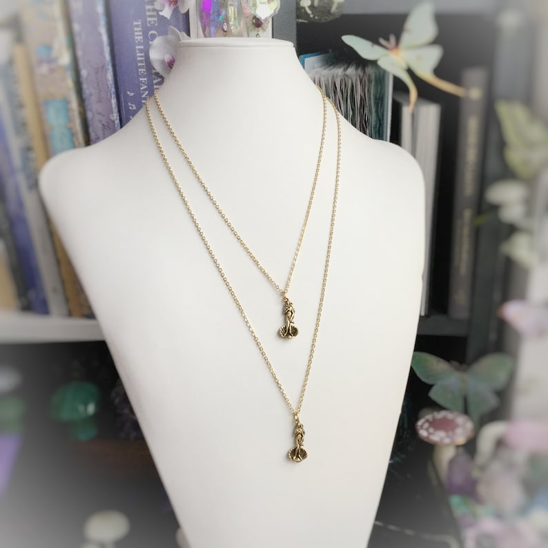 May include: A gold chain necklace with two small, delicate charms. The charms are shaped like a flower with three petals.