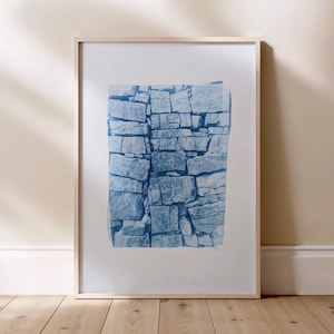 May include: A framed cyanotype print of a blue and white stone wall. The print is in a light wood frame.