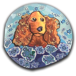 May include: A hand-painted ceramic plate featuring a colourful cocker spaniel dog illustration on a blue background with a swirling pattern.
