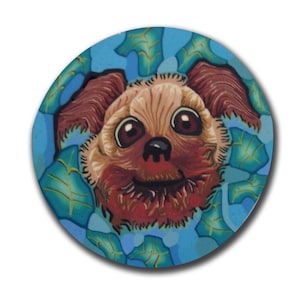 May include: A close-up of a brown and tan dog with big brown eyes. The dog is smiling and has a red nose. The dog is surrounded by blue and green leaves.