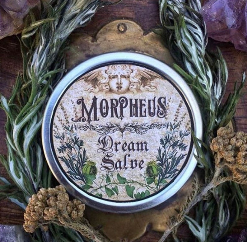 May include: A silver tin with a vintage label that reads "Morpheus Dream Salve". The label features a stylised image of a woman's face with wings and floral designs.