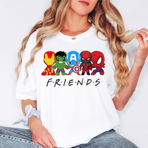 K&ouml;nnte beinhalten: Wei&szlig;es T-Shirt mit einem Aufdruck von f&uuml;nf Comic-Superhelden, darunter Iron Man, Hulk, Captain America, Black Panther und Spiderman. Der Text "FRIENDS" ist unter den Superhelden aufgedruckt.