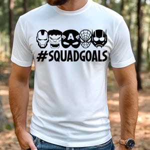 May include: White t-shirt with a black graphic of superhero faces and the text "#SQUADGOALS".
