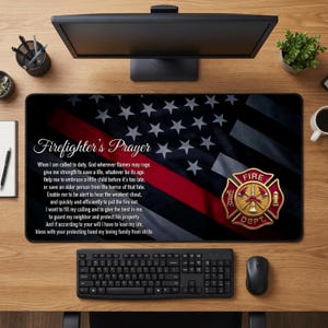 Pode incluir: Tapete de mesa preto e cinza com um design estilizado da bandeira americana, uma faixa vermelha e estrelas brancas. O texto "Firefighter's Prayer" é exibido, juntamente com um emblema do corpo de bombeiros.