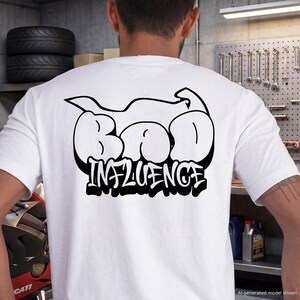 May include: A white short-sleeved t-shirt featuring a large black graphic on the back. The design displays the text "BAD INFLUENCE" in a bold, bubble-style graffiti font, positioned beneath a stylized black outline of a motorcycle silhouette.