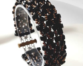 Pulsera hecha a mano con puntada de espiga, cuentas de semillas de bronce y triángulos negros