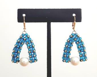 Pendientes de cuentas de semillas tejidas a mano en turquesa azul y oro con perla blanca de Swarovski