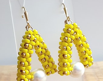 Pendientes de cuentas de semillas tejidas a mano en amarillo y dorado con perla blanca de Swarovski
