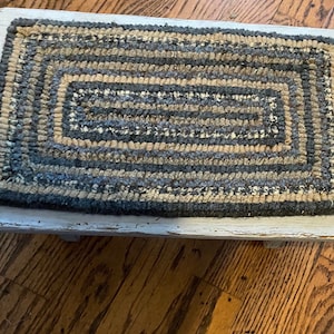 Primitive style geometric hooked rug runner on a painted gray footstool