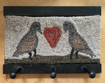 Hand hooked rug with two birds and heart on a painted wood wall hanger with pegs