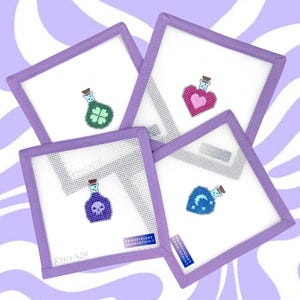 May include: Four square needlepoint coasters with purple borders and white mesh centers. Each coaster features a different potion bottle design: a four-leaf clover, a heart, a skull, and a moon with stars. The coasters have the text "FRIDAY NIGHT NEEDLEPOINT" and "FNN-42P".