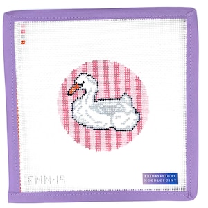 May include: A needlepoint canvas featuring a white swan with an orange beak, set against a pink and white striped circle. The canvas is framed in lavender and includes the text "FRIDAY NIGHT NEEDLEPOINT".