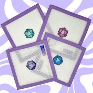 May include: Four square coasters with a white center and a purple border. Each coaster features a different colored geometric design in the center. The coasters are arranged on a purple and white swirled background.
